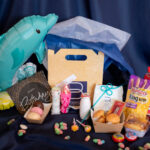 PequeBox de Bizzancio mostrando bollería gourmet, bocados salados, bebidas lácteas y chucherías, todo esto con decoración festiva de fondo. Perfecta para desayunos a domicilio o regalos gourmet para niños.