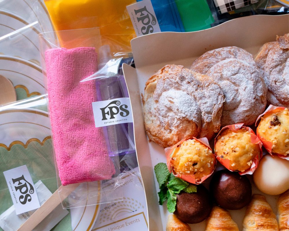 Detalle de utensilios desechables y Bandeja Solo Dulces Bizzancio para un desayuno a domicilio gourmet en oficina.