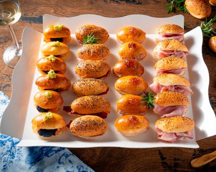 Presentación de la Bandeja de Mediasnoches Gourmet Bizzancio con pan artesanal y rellenos premium, cuidados bocados para un desayuno o comida a domicilio gourmet.