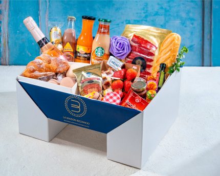 Pedestal Box Bizzancio con botella extra de cava presentada con su variedad de bollería gourmet, embutidos y bebidas, perfecta para desayunos a domicilio o regalos especiales.